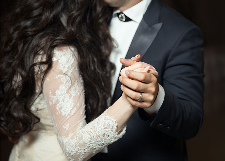 Couple just married holding hands and emphasizing their wedding bands as they dance