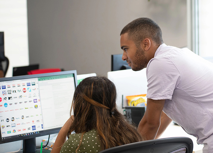 Professor looking over a student's shoulder as they work on a computer